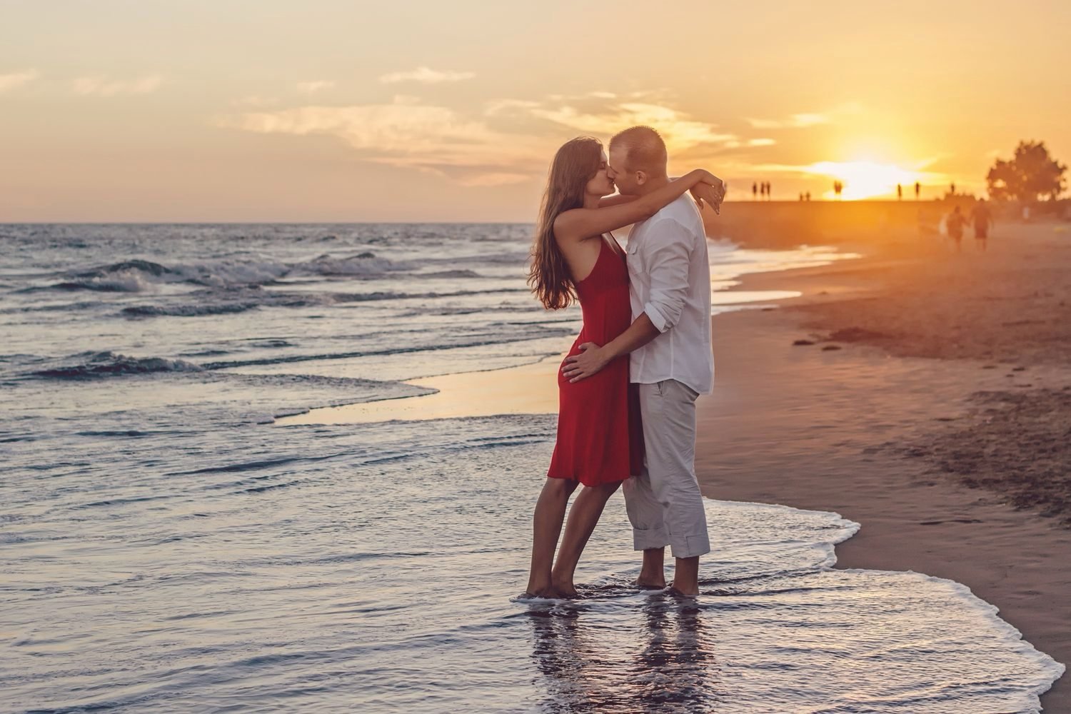 Un couple enlacé sur la plage au coucher du soleil